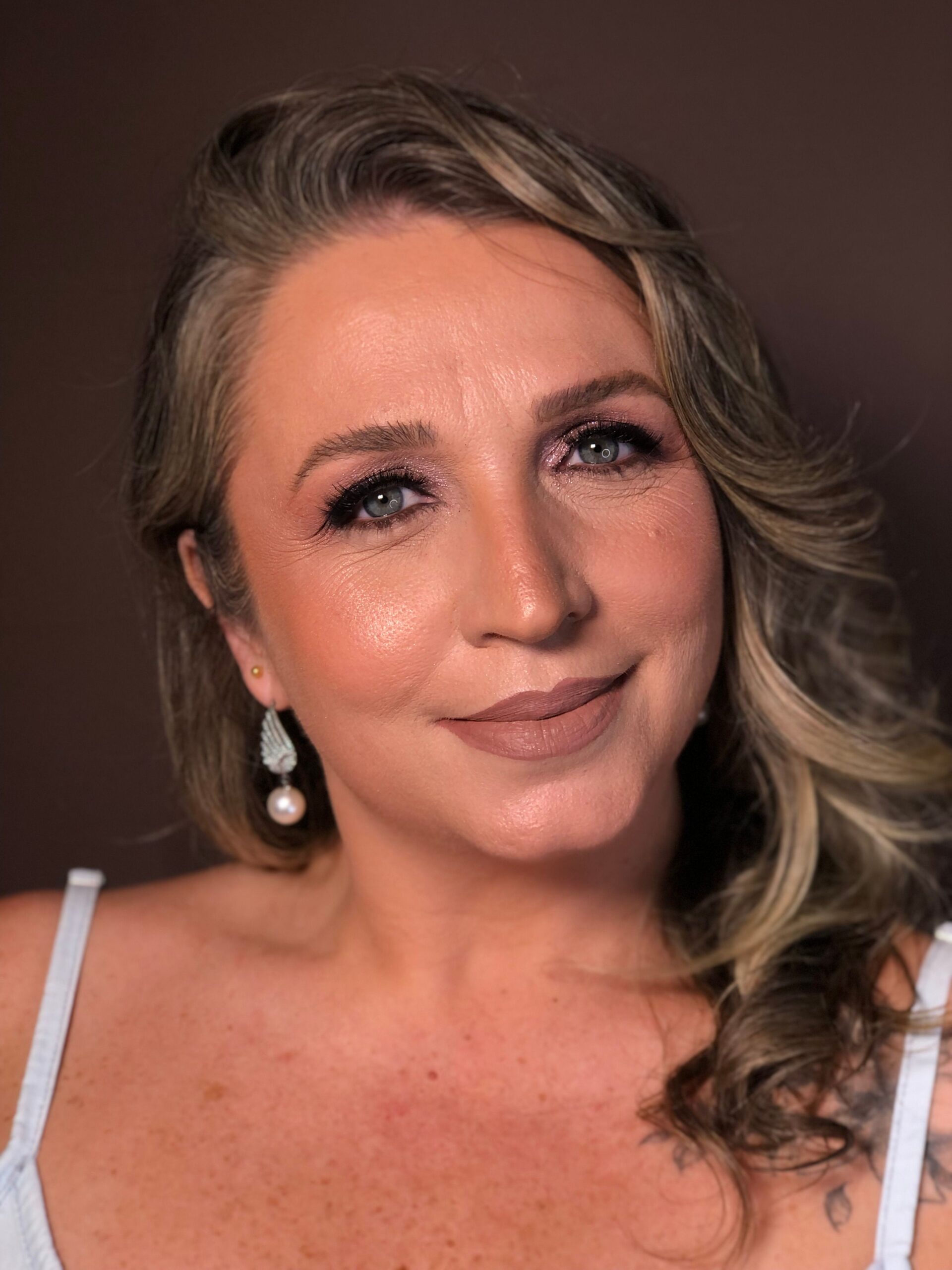 A close-up portrait of a smiling woman with elegant makeup and hairstyle.